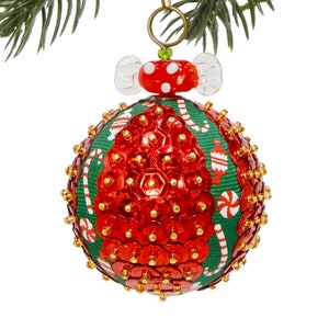 May include: A spherical Christmas ornament featuring a green fabric base decorated with red sequins and a pattern of candy canes and wrapped sweets. The top is adorned with a red and white polka dot glass bead and a gold metal hanging loop.