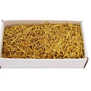 May include: A white box filled with a large quantity of gold-colored straight pins with round heads.