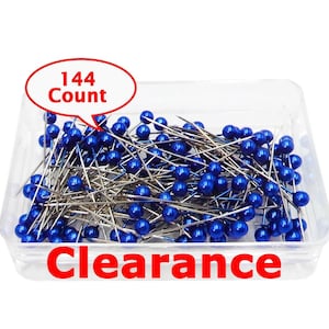 May include: A clear plastic container filled with 144 count blue ball-head sewing pins. The pins feature metallic silver shafts and round, glossy blue heads. The text 144 Count appears in a red speech bubble, and the word Clearance is in red.