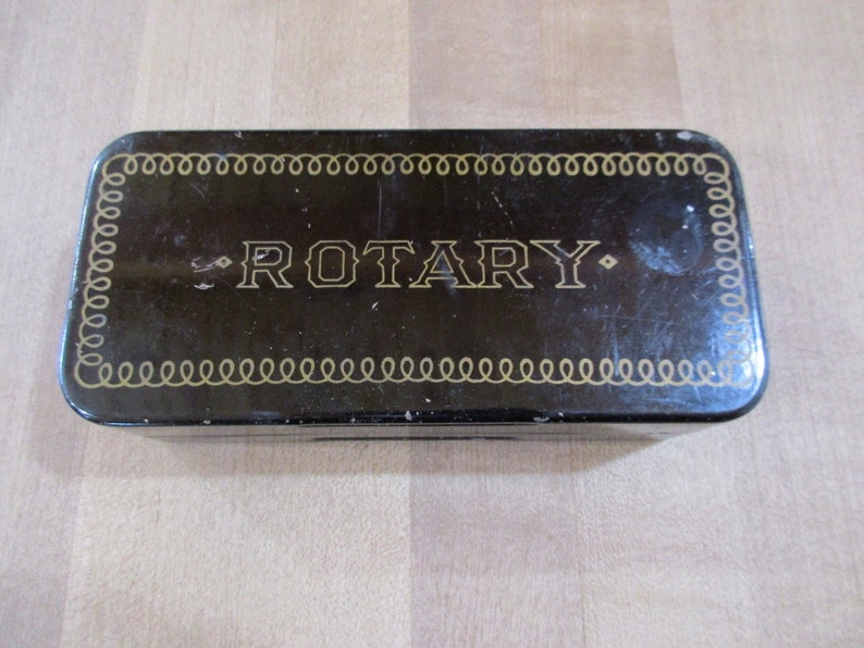 May include: A black metal box with a gold border and the word "ROTARY" printed in gold letters.