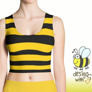 May include: A yellow and black striped crop top with a scoop neck. The top is made of a stretchy fabric and has a casual fit. The model is wearing the top with a yellow skirt.