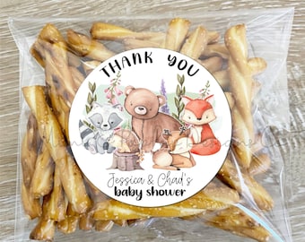 May include: Thank you favour bag with a round sticker featuring a watercolour illustration of woodland animals, including a raccoon, bear, hedgehog, deer, and fox. The sticker says "Thank You" and "Jessica & Chad's Baby Shower".