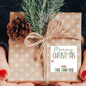 May include: A brown gift box with white polka dots is wrapped with twine and a sprig of green pine. A white gift tag with red and green lettering reads "Merry Christmas" and "From: The Smiths".