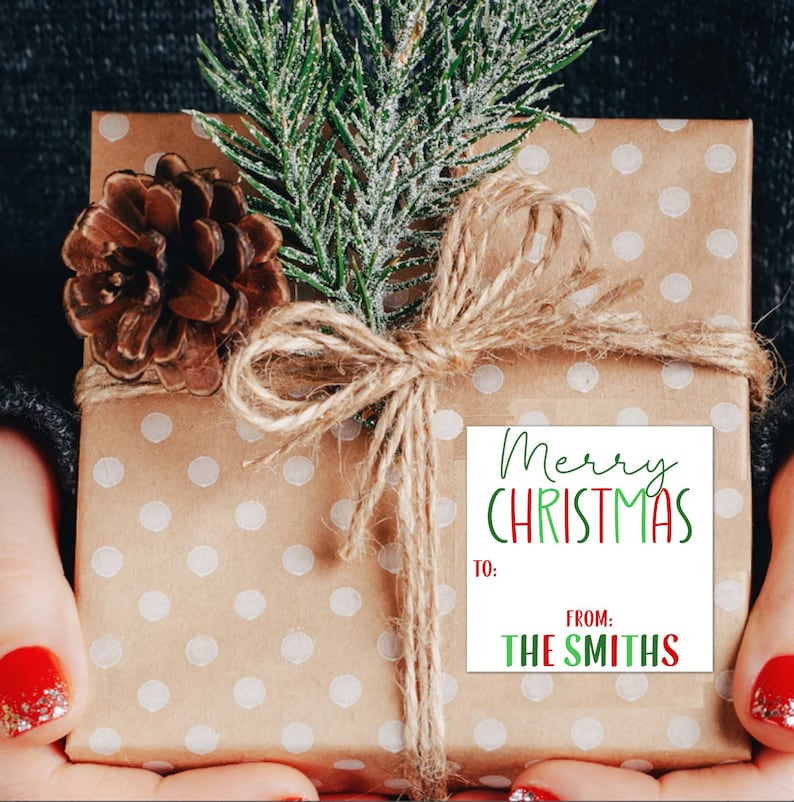 May include: A brown gift box with white polka dots is wrapped with twine and a sprig of green pine. A white gift tag with red and green lettering reads "Merry Christmas" and "From: The Smiths".
