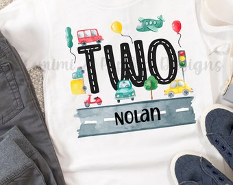 May include: White t-shirt with a black "TWO" on a road with cars, a plane, and balloons. The name "Nolan" is written below the number.