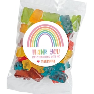 May include: A clear plastic bag filled with colorful gummy bears. A round sticker with a rainbow design and the text "THANK YOU FOR CELEBRATING WITH ME ♥ MARIANNA" is attached to the bag.
