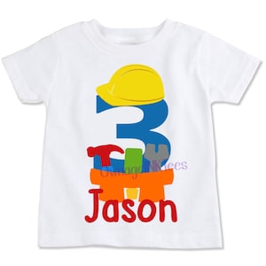 May include: White t-shirt featuring a blue number 3, a yellow hard hat, and colourful tools. The name "Jason" is written in red below the tools.