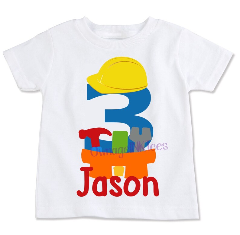 May include: White t-shirt featuring a blue number 3, a yellow hard hat, and colourful tools. The name "Jason" is written in red below the tools.
