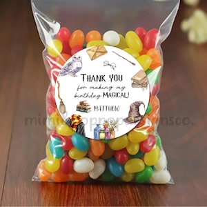 May include: A white round sticker with a black border and a watercolor illustration of a wizarding theme. The sticker says "Thank you for making my birthday magical!" with the name "Matthew" below the text. The sticker is on a clear plastic bag filled with colorful jelly beans.