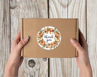 May include: Round sticker with a wreath of pumpkins and white flowers. The sticker has the text "thank you" in the center.