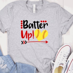 May include: Gray t-shirt with the text "Batter Up!" in black and red, featuring a yellow softball in a heart shape with red stitching.