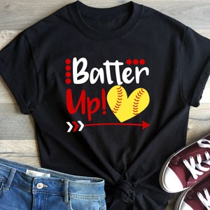 May include: Black t-shirt with white text that says "Batter Up!" and a red arrow pointing to the right. A yellow softball in the shape of a heart is above the arrow.