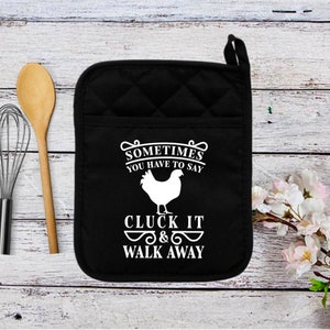 May include: Black quilted oven mitt with a white chicken silhouette and the text "Sometimes you have to say Cluck It & Walk Away".