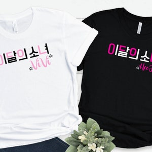 May include: Two t-shirts with the Korean text "이름소녀" and the names "Vivi" and "Hee Jin" in pink lettering on a white and black shirt.