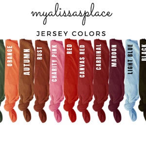 Puede incluir: Una fila de muestras de tela en varios colores, incluyendo azul marino, verde militar, naranja, oto&ntilde;o, &oacute;xido, rosa caridad, rojo, rojo de lona, cardenal, granate, azul claro, negro y blanco. Las muestras est&aacute;n atadas en nudos y etiquetadas con sus nombres de color correspondientes.