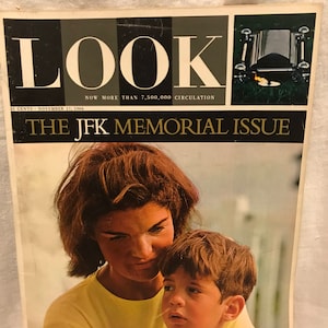 Pode incluir: Uma capa de revista com uma foto em preto e branco de Jacqueline Kennedy Onassis e seu filho John Jr. A capa diz "LOOK" e "THE JFK MEMORIAL ISSUE".
