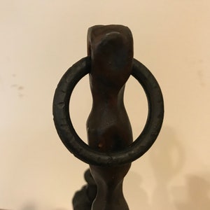 Puede incluir: Una escultura de metal negro con un anillo en la parte superior. La escultura es abstracta y tiene una forma retorcida y org&aacute;nica.