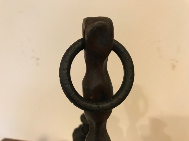 Puede incluir: Una escultura de metal negro con un anillo en la parte superior. La escultura es abstracta y tiene una forma retorcida y org&aacute;nica.