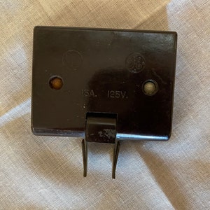 Puede incluir: Un fusible eléctrico negro con una etiqueta blanca que dice "15A. 125V."