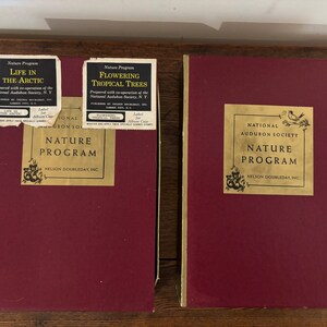 May include: Two red boxes with gold lettering. The boxes are labelled "National Audubon Society Nature Program" and "National Audubon Society Nature Program". The boxes are part of a nature program.