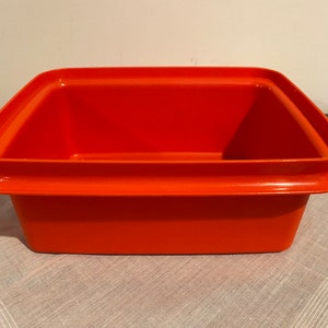 May include: A bright orange plastic storage container with a wide rim and a rectangular shape.