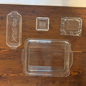 Könnte beinhalten: Vier transparente Glasbackformen in verschiedenen Größen und Formen. Die Formen befinden sich auf einer Holzoberfläche.