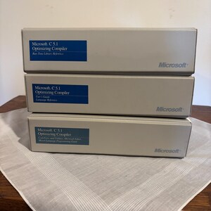 May include: Three beige boxes stacked on top of each other. Each box has a blue label with white text that reads "Microsoft C 5.1 Optimizing Compiler". The boxes are labeled "Run-Time Library Reference", "User's Guide", and "CodeView and Utilities". The Microsoft logo is on each box.