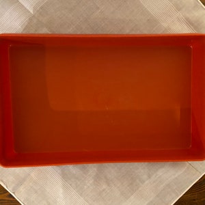 Puede incluir: Un molde para hornear rectangular de color naranja con un acabado liso y brillante. El molde está vacío y listo para hornear.