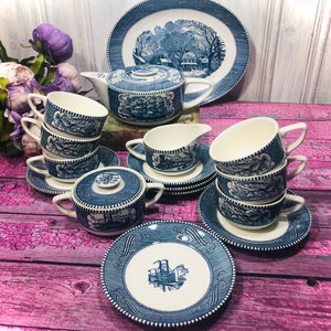 May include: A vintage blue and white tea set with a winter scene design. The set includes a teapot, creamer, sugar bowl, cups, and saucers.