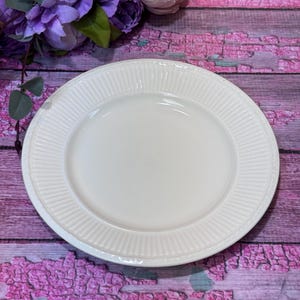 Può includere: Un piatto in ceramica bianca con bordo a coste. Il piatto ha un design semplice ed elegante, adatto per servire i pasti. Il piatto è rotondo e sembra nuovo.