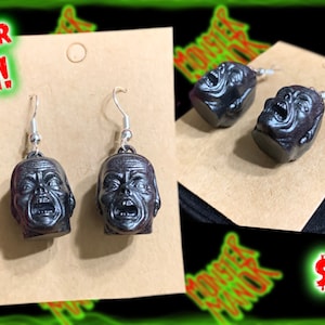 May include: A pair of black screaming head earrings on a brown card with the text "NEW FOR 2024!" and "$15.00".