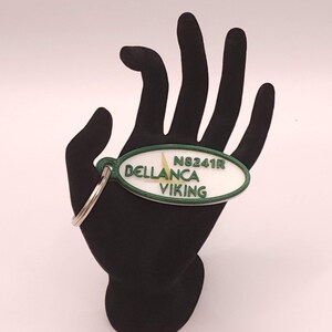 May include: White oval keychain with green trim and the text "N8241R DELLANCA VIKING" in black.
