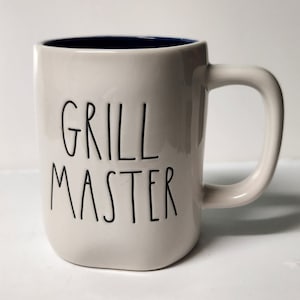 May include: White ceramic mug with a blue rim and black text that reads "Grill Master".
