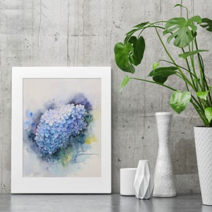 May include: A watercolor painting of a blue hydrangea flower in a white frame. The painting is set against a gray concrete wall with a green plant in a white vase.