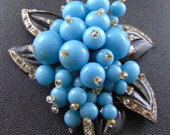 May include: A blue and black brooch featuring a cluster of blue glass beads in the shape of a flower.