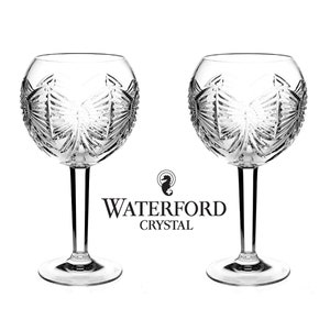 May include: Two clear crystal wine glasses with a cut glass design. The glasses are on a white background with the text "Waterford Crystal" below them.