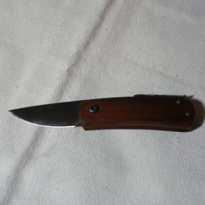 May include: A small, brown wooden handled pocket knife with a silver blade.