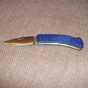 May include: A blue and gold pocket knife with a curved handle and a partially open blade.