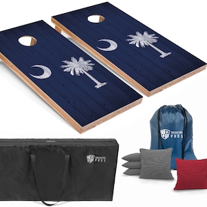 May include: A set of two regulation-sized cornhole boards with a custom design featuring the South Carolina state flag. The boards are made of wood and have a blue and white finish. The set also includes a carrying case, a bean bag toss bag, and eight bean bags. The bean bags are in two colors: gray and red.