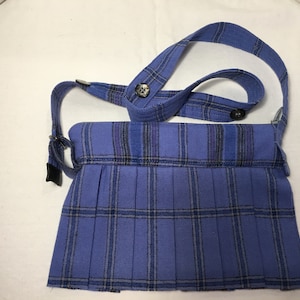 May include: A blue plaid crossbody bag with a pleated front and a long strap. The strap has two buttons.