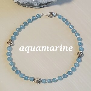 May include: A light blue beaded anklet with silver turtle charms. The anklet has a silver lobster clasp.