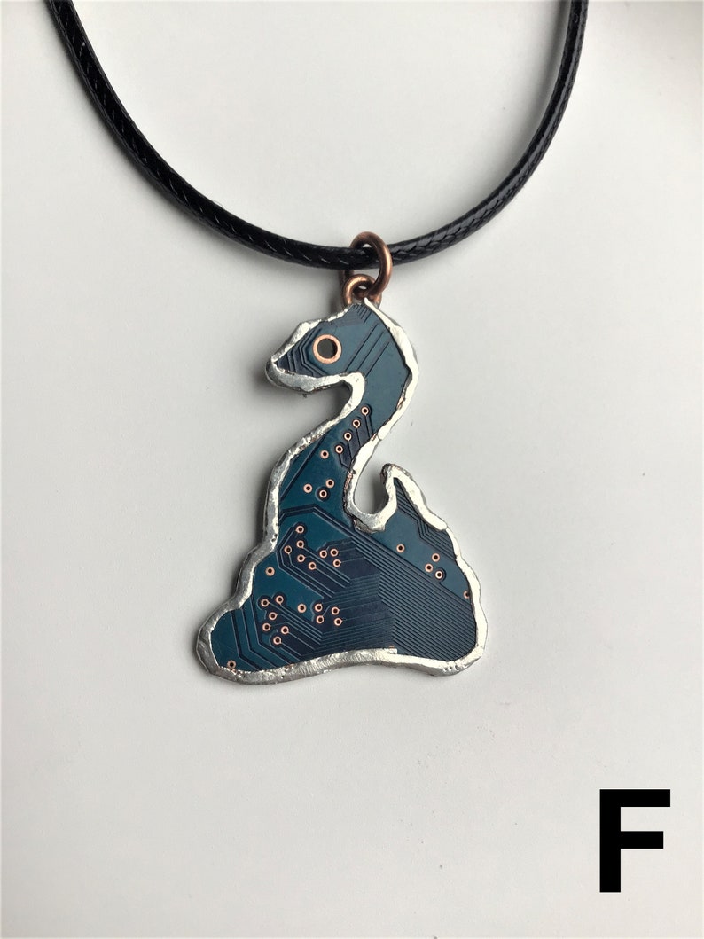 May include: A dark blue circuit board pendant shaped like a snake, with copper accents, hanging from a black cord.