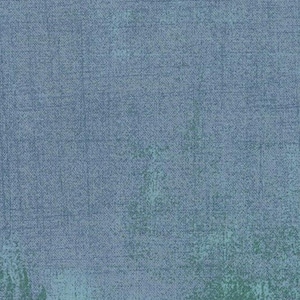 May include: A textured fabric with a mottled appearance. The background is a muted blue, with areas of green and lighter blue. The fabric has a subtle grid pattern, giving it a vintage or distressed look.