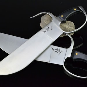 May include: Two silver-colored swords with black handles and gold accents. The swords are crossed and have Chinese characters inscribed on the blades.