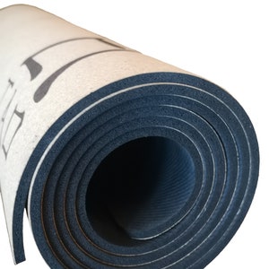 Op de afbeelding: Opgerolde yogamat met een witte bovenkant en een zwarte onderkant. De mat heeft een textuur en is strak opgerold.