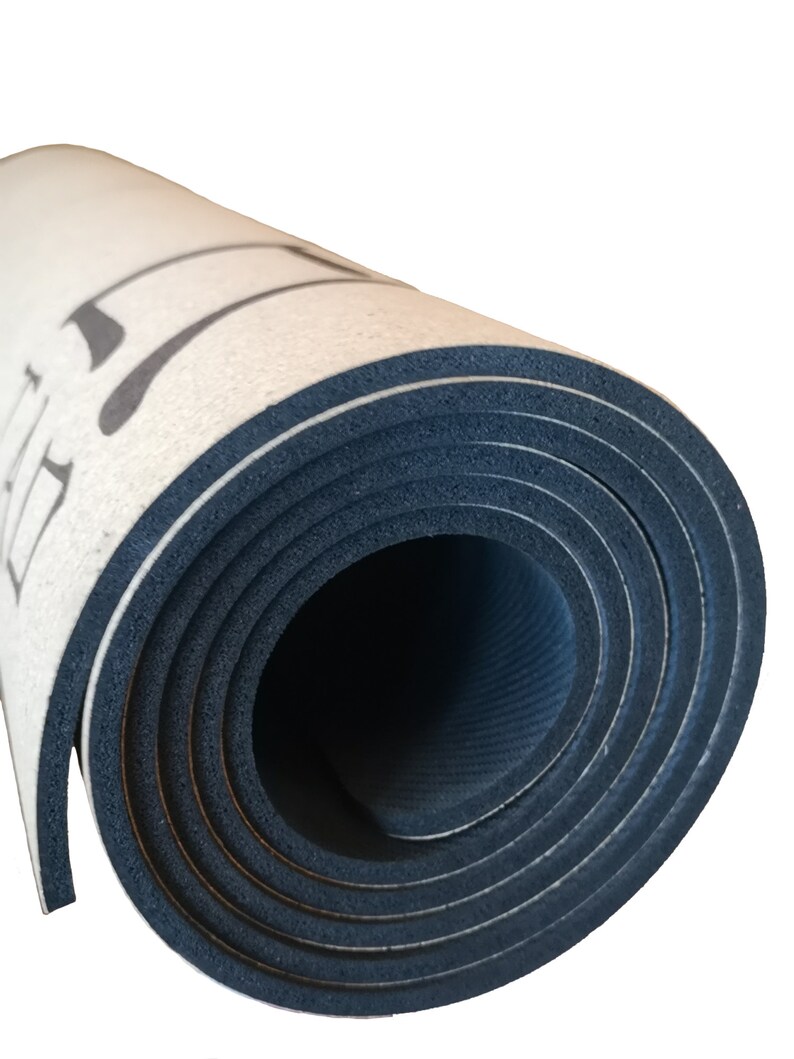 Op de afbeelding: Opgerolde yogamat met een witte bovenkant en een zwarte onderkant. De mat heeft een textuur en is strak opgerold.