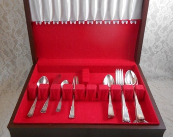 May include: A wooden box with a red velvet interior and a white satin lining. The box contains a set of silverware, including forks, knives, and spoons.