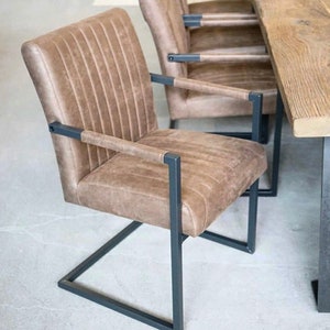 May include: A brown leather dining chair with a metal frame. The chair has a square back and a curved seat. The chair is on a light grey floor.