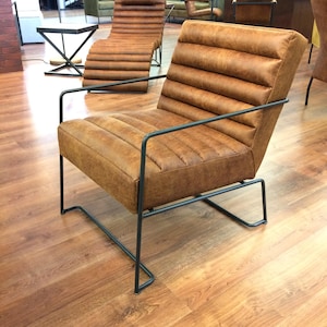 May include: A brown leather armchair with a black metal frame. The chair has a tufted back and seat.