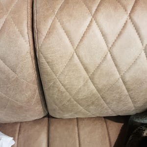 Puede incluir: Primer plano de un sof&aacute; marr&oacute;n claro con un patr&oacute;n capiton&eacute; en forma de diamante. El sof&aacute; tiene una textura lisa, similar al cuero.